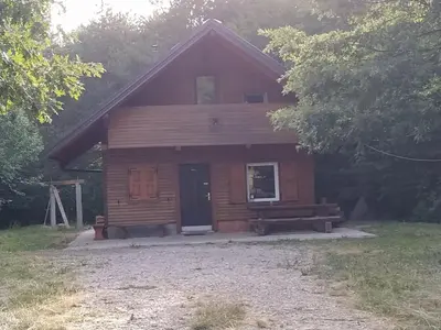 a log cabin with a bench in front of it at Podklanci-house in the forest in Knežak