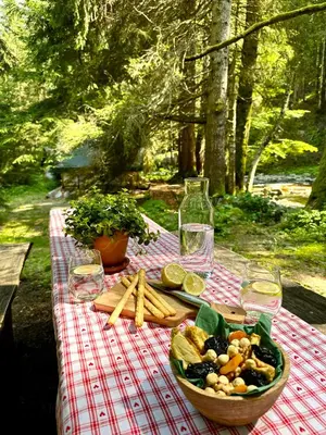 a picnic table with a bowl of food and wine glasses at Glamping Tent Water Village Rogla in Oplotnica