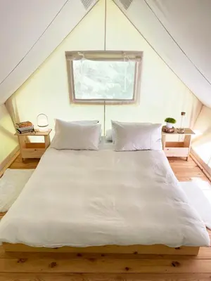 a large white bed in a room with a window at Glamping Tent Water Village Rogla in Oplotnica