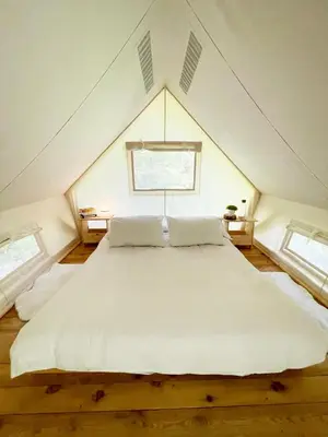 a large white bed in a room with two windows at Glamping Tent Water Village Rogla in Oplotnica