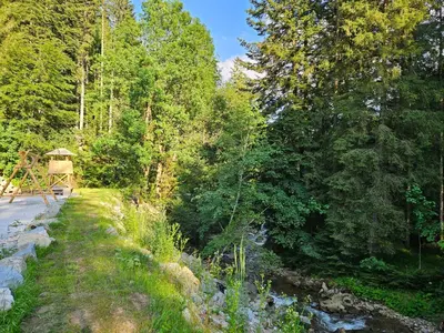 a river next to a forest with a gazebo at Glamping Tent Water Village Rogla in Oplotnica