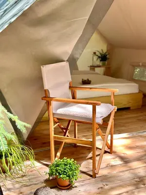 a chair and a table in a room with a bed at Glamping Tent Water Village Rogla in Oplotnica