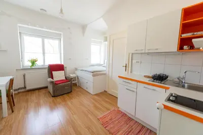 a kitchen with white cabinets and a table and a chair at Soska 5 in Ljubljana