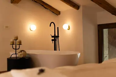 a bath tub in a bathroom with two lights on the wall at Škerlj Wine Estate in Tomaj