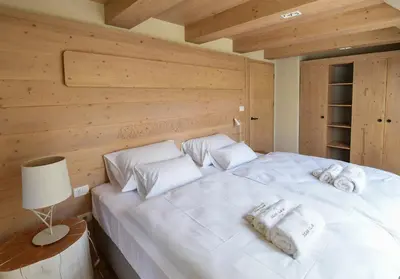 a bedroom with a white bed with a wooden wall at JULIAN VILLAGE LEPENA in Soča