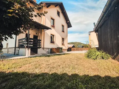 a large white building with a yard in front of it at Apartments STARI TIGER in Bohinj