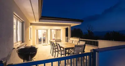 a balcony with a table and chairs and a grill at Villa Vitovlje in Vitovlje