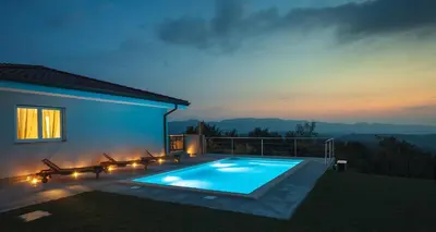 a swimming pool in front of a house at night at Villa Vitovlje in Vitovlje