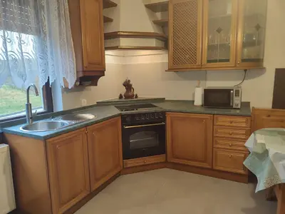 a kitchen with wooden cabinets and a sink and a microwave at Hiša Žičanka in Loče pri Poljčanah