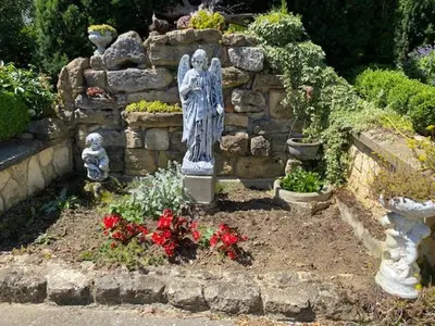 a statue of a woman in a garden with flowers at Apartma Jožica in Tonček in Sveti Jurij ob Ščavnici