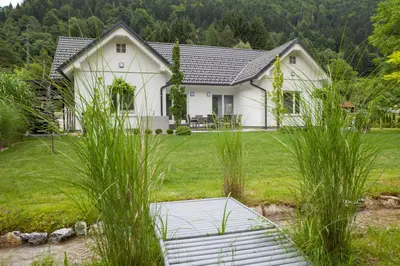 a white house with a yard with tall grass at Bella Belca in Mojstrana