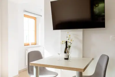 a white dining room table with chairs and a vase of flowers at STUDIO BELA in Radovljica