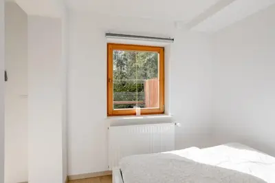 a white bedroom with a window and a bed at STUDIO BELA in Radovljica