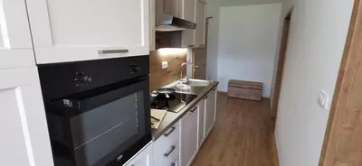 a kitchen with white cabinets and a black appliance at Apartmaji Tmaynka in Tolmin