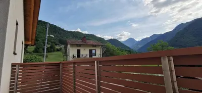 a house with a fence and mountains in the background at Apartmaji Tmaynka in Tolmin