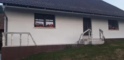 a white house with two windows and flowers in windows at Francek house Podčetrtek in Buče