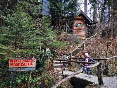 a woman standing on a bridge in front of a log cabin at Francek house Podčetrtek in Buče