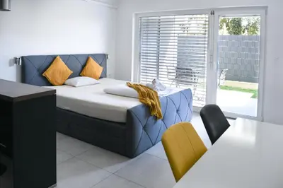 a bedroom with a bed with a blue headboard and chairs at Point Zero in Ljubljana