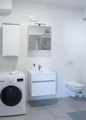 a white bathroom with a washing machine and a sink at Point Zero in Ljubljana