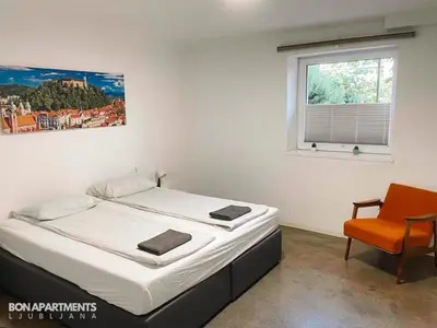 a bedroom with a bed and a chair and a window at Huge BBQ Garden 1, Basement app Two Bathrooms, AC, Free Parking in Ljubljana