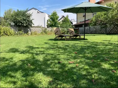 a table and chairs under an umbrella in a yard at Huge BBQ Garden 1, Basement app Two Bathrooms, AC, Free Parking in Ljubljana