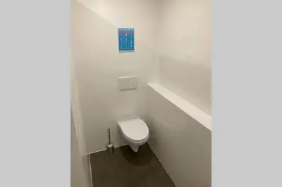a bathroom with a toilet with a blue sign on the wall at Huge BBQ Garden 1, Basement app Two Bathrooms, AC, Free Parking in Ljubljana