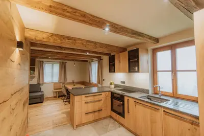 a kitchen with wooden cabinets and a dining room at Cottage Planska koča in Vitanje