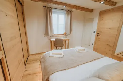 a bedroom with a bed with a chair and a window at Cottage Planska koča in Vitanje