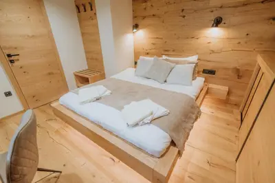 a large bed in a room with wooden walls at Cottage Planska koča in Vitanje