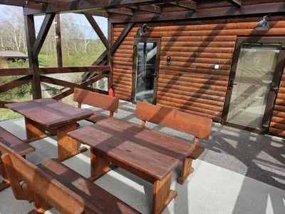 a picnic table and benches on a porch of a cabin at River Houses Ljubljanica in Ljubljana