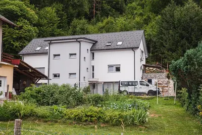 a white house with a car parked in front of it at Apartments Rozalija in Preddvor