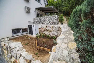 a stone retaining wall next to a house at Apartments Rozalija in Preddvor