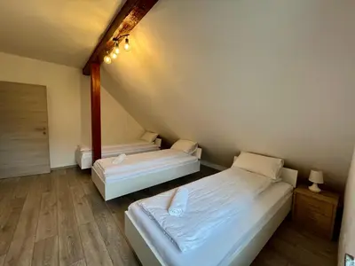 two beds in a small room with wooden floors at Two Panorama Apartments in Bovec