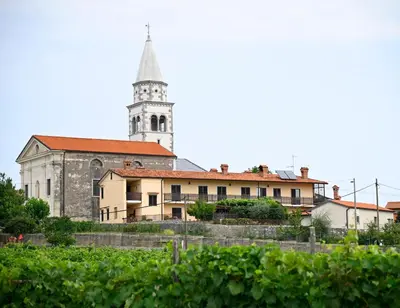 an old building with a church with a tower at Apartma Čuk in Dutovlje