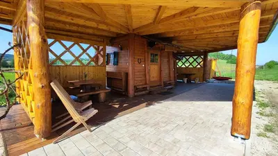 a large wooden cabin with a bench and a table at Unique wooden holiday house in nature in Lukovica pri Domžalah