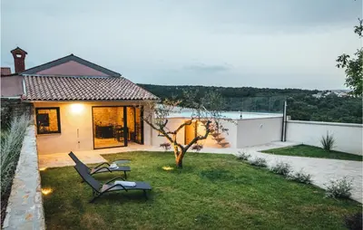 a backyard with two lawn chairs and a tree at Beautiful Home In Skofije in Plavje