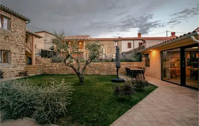 a backyard with a brick wall and a table and a tree at Beautiful Home In Skofije in Plavje