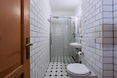 a white tiled bathroom with a toilet and a sink at Hiša Orel (Orel House) in Križ