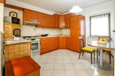 a kitchen with wooden cabinets and a table and a window at Danilo's Resort, Vipavska dolina in Dobravlje