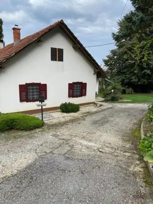 a white house with red windows on a gravel road at Živahna hiša in Sveti Jurij ob Ščavnici