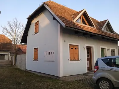a small white house with orange doors and a car at Čebelica, apartma 101, Terme Čatež in Brežice