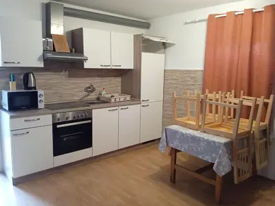 a kitchen with white cabinets and a stove and a table at Čebelica, apartma 101, Terme Čatež in Brežice