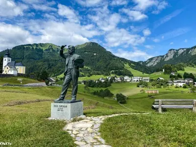 a statue of a man on a field with mountains at Apartma Ajda in Železniki