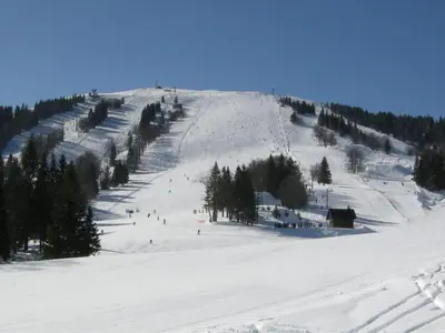 a snow covered hill with people skiing on it at Apartma Ajda in Železniki