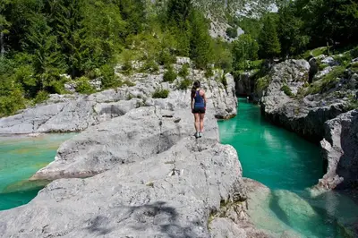a woman standing on a rock near a river at Apartma Ajda in Železniki