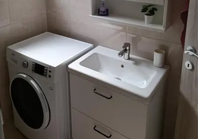 a bathroom with a sink and a washing machine at Studio Mici in Bled
