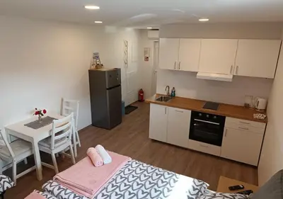 a kitchen with a table and a small kitchen with white cabinets at Studio Mici in Bled