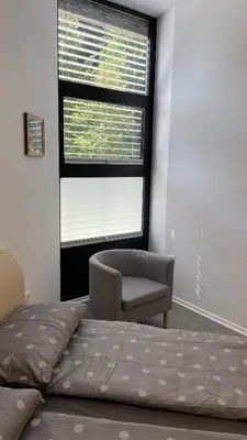 a bedroom with a bed and a chair and a window at Simba Apartment B in Smarjeske Toplice