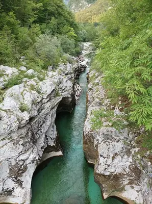 a river between two large rocks with green water at OASIS in Bovec