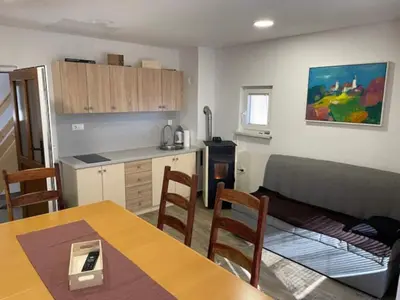 a living room with a table and a kitchen at Holiday House Zlačka Gorca in Pristava pri Mestinju